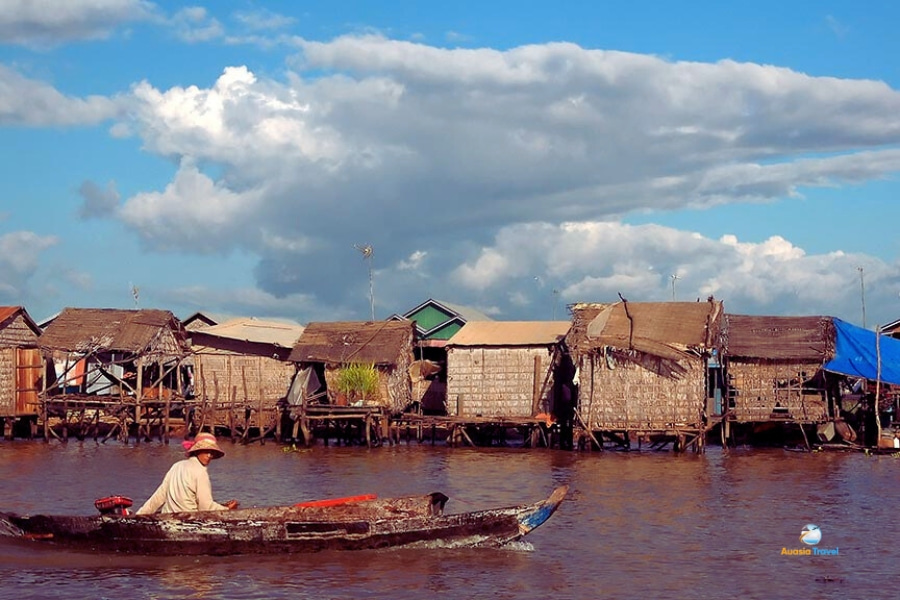 Local man rowing boat past stilt houses on Tonle Sap Lake Cambodia – Auasia Travel